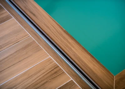 Vue rapprochée d'un bord de piscine en bois avec une couverture en verre turquoise.