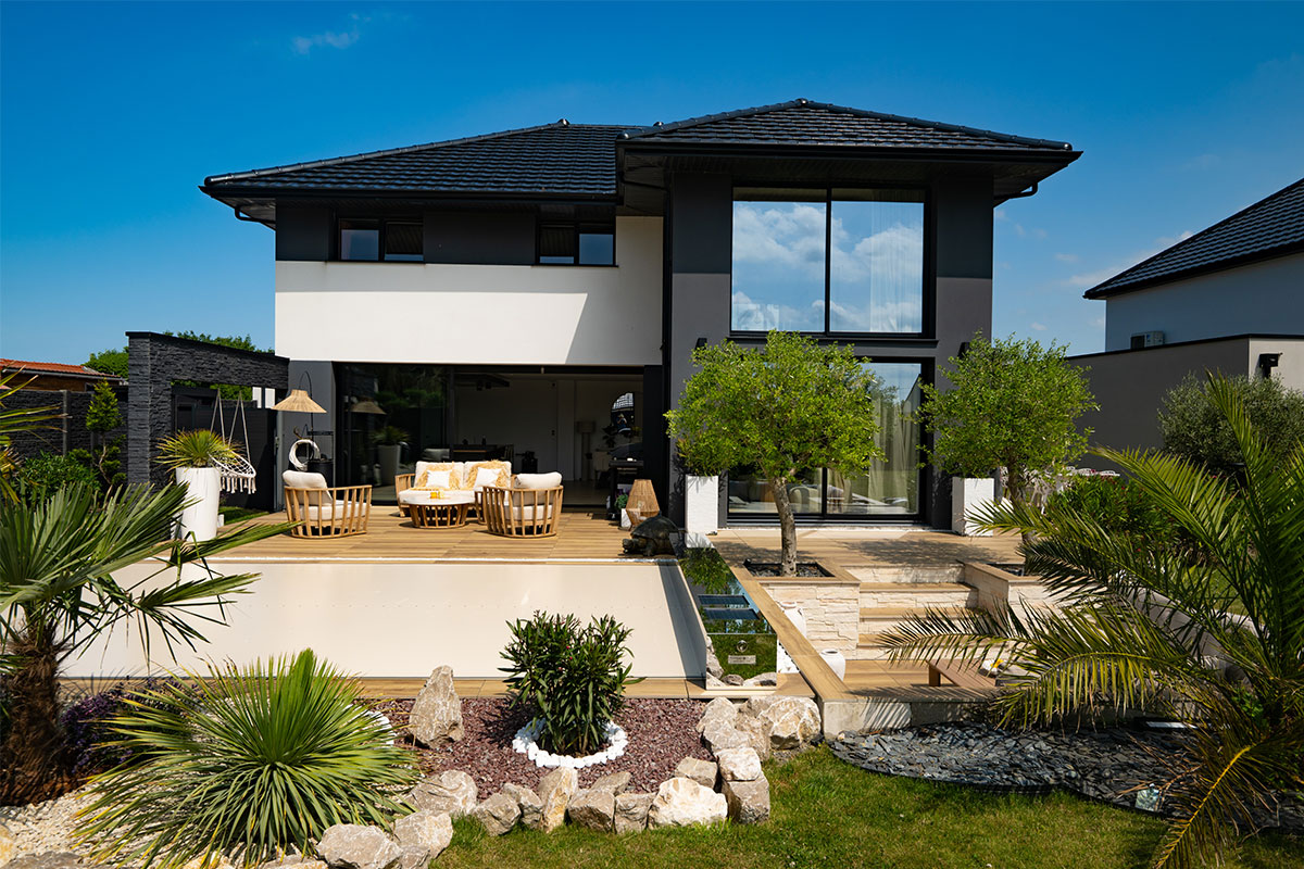 Maison moderne avec grande baie vitrée donnant sur une terrasse bois et une piscine protégée par une couverture Coverseal premium.