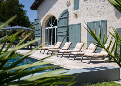 Vue latérale de la terrasse avec transats alignés au bord de la piscine, équipée d’une Coverseal grise discrète et moderne.
