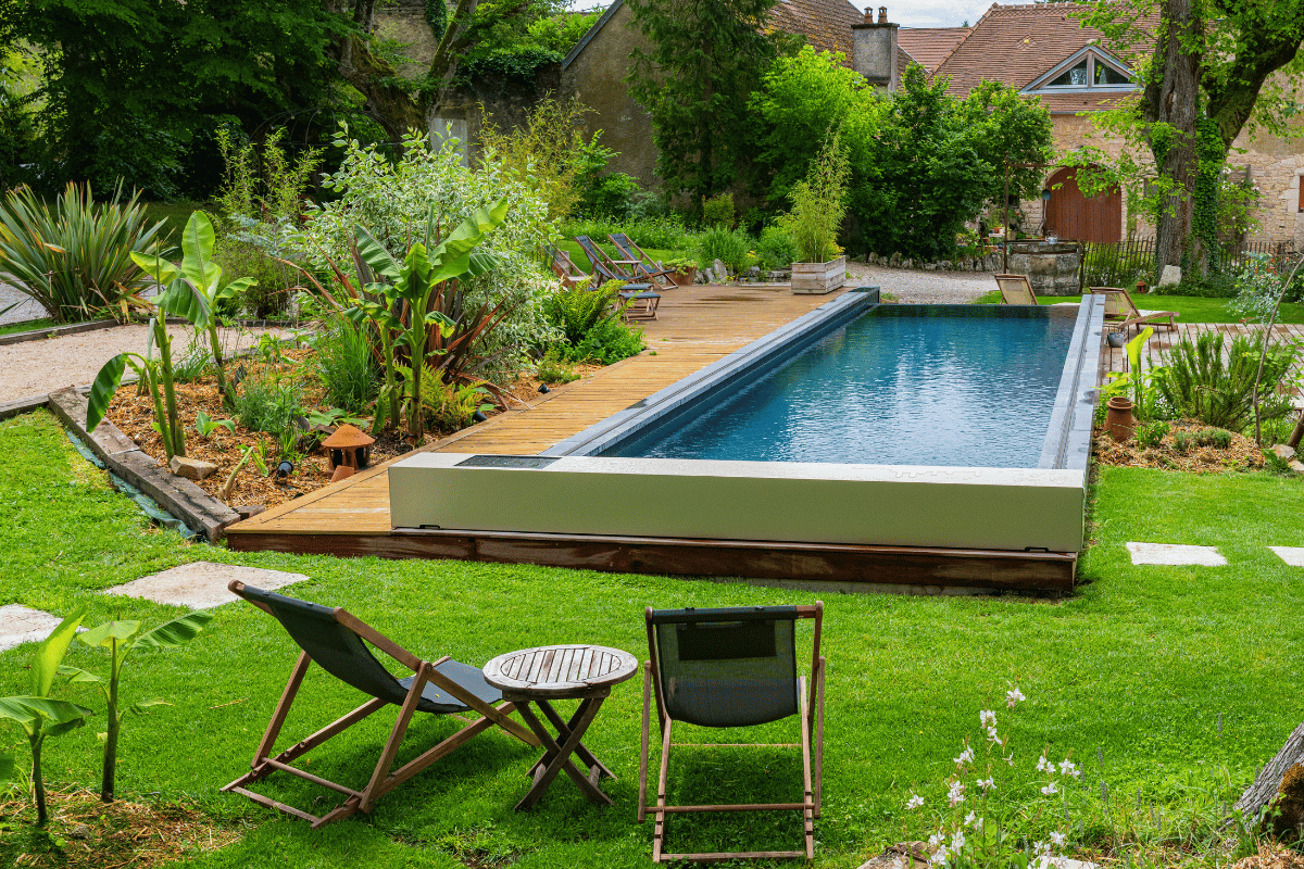 Gros plan sur l'habillage de la Coverseal grise au bord de la piscine, avec en arrière-plan les transats et la maison en pierre.
